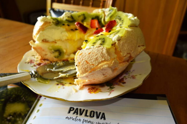A fruity pavlova on a plate cut and eaten with a spoon